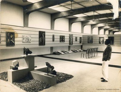 **Tyeb Mehta, 1959, Gallery 1959**
Photograph of Tyeb Mehta as he stands looking at the display of his first solo exhibition in 1959, organised by Gallery 59, Bombay. Inscribed with year and location in pencil on the reverse.